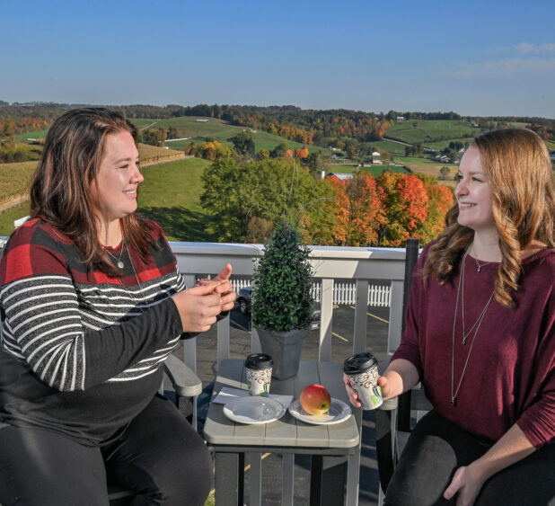 Two women on a patio with rolling hills in background